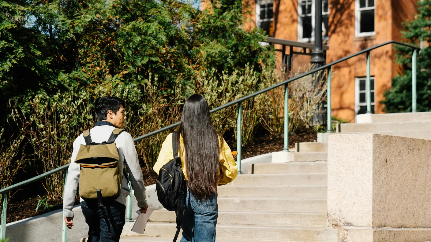 Two students walking together on a college campus pathway